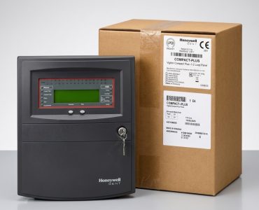 Honeywell Gent control panel with green LCD screen beside a large brown shipping box.