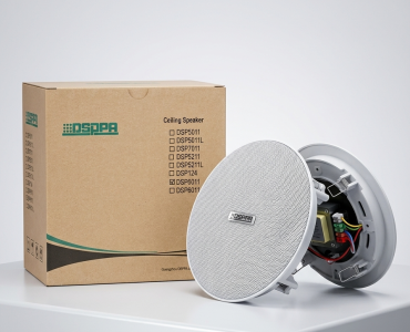 Ceiling speaker product with its open box showing wiring and connector, placed on a white surface.